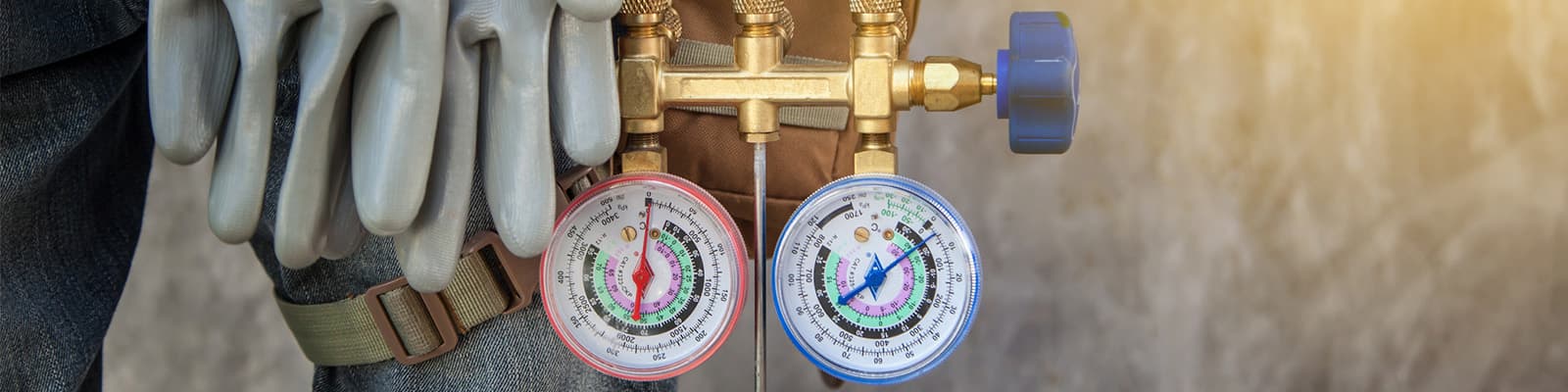 This is a closeup of an HVAC technician's work gloves and temperature gages.
