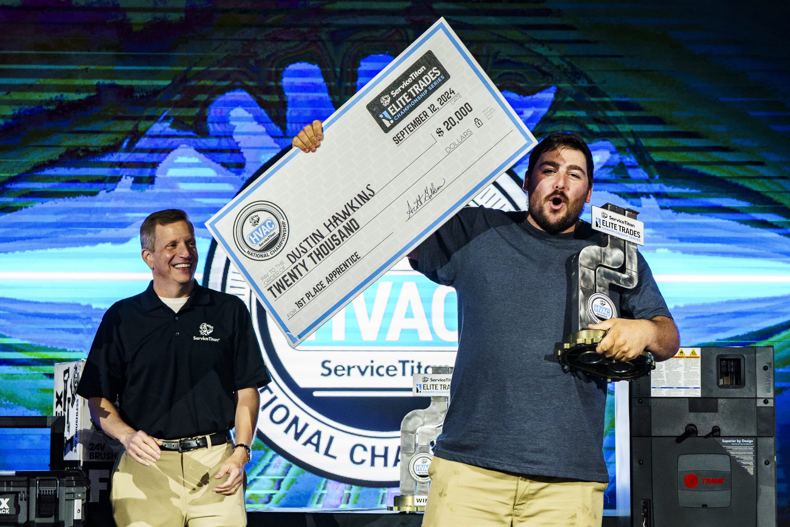 A competition winner stands on stage as he's presented with a large prize check.