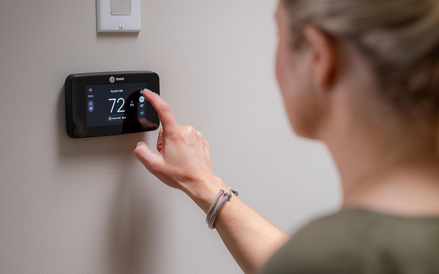 Woman adjusting a thermostat