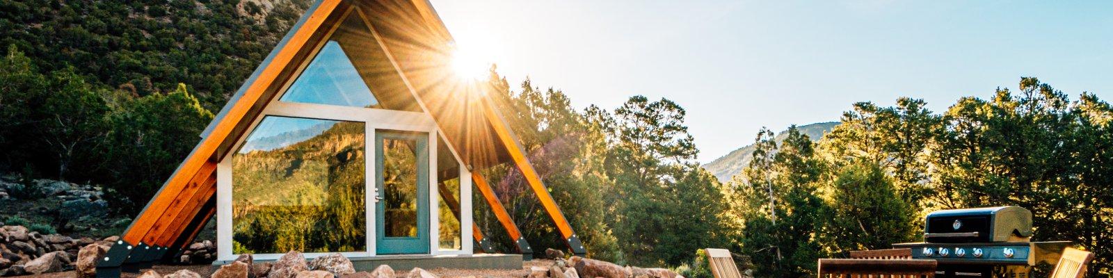 The front windows of a small triangular house are reflecting the sun.