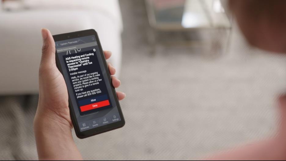 A person is holding their phone with the Trane Home App.