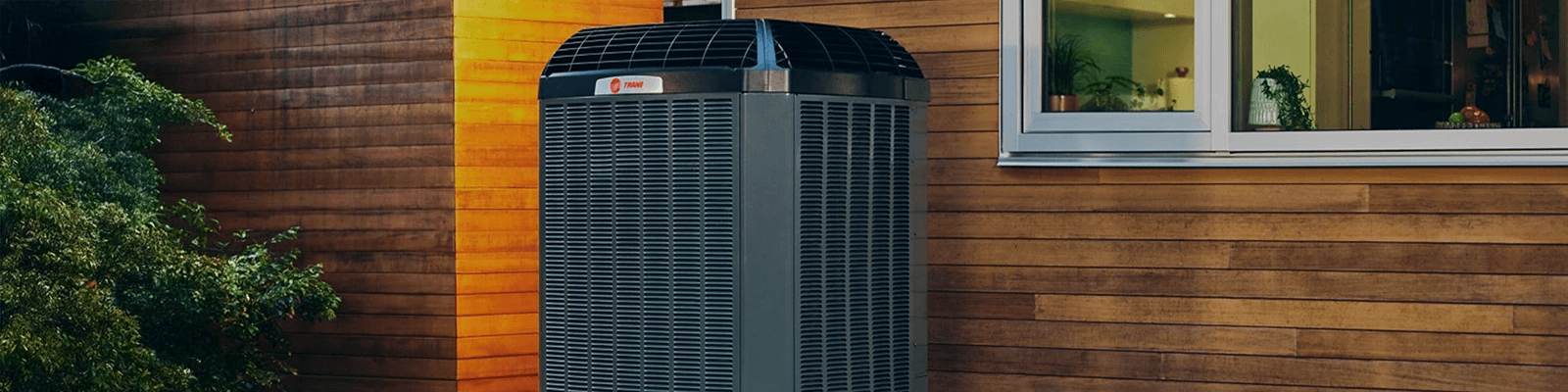 A Trane outdoor unit sits outside of a home.